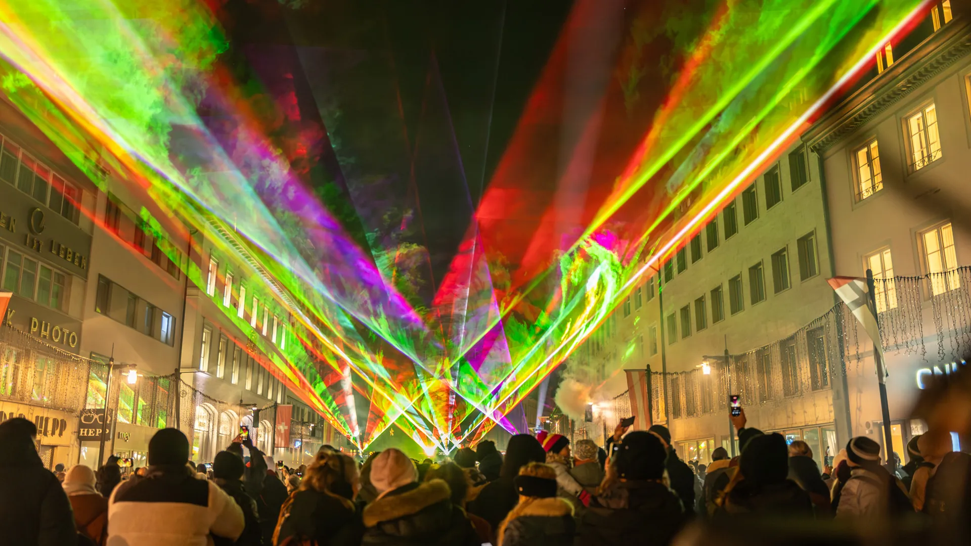 Lasershow in einer Altstadtstraße: rote, grüne und gelbe Strahlenfächer über dem Publikum